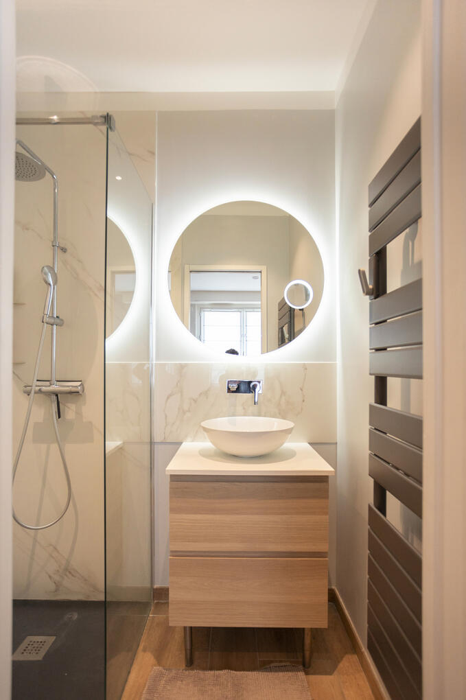 Salle de bain Salle de bain moderne, contemporaine avec son miroir LED circulaire et des matériaux chaleureux